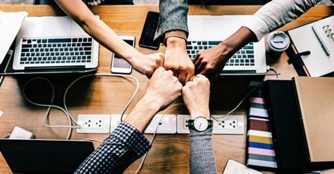 Fem personer slår deres knyttede næver sammen.