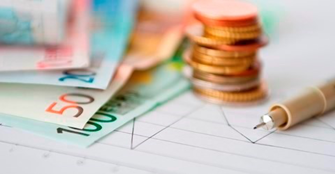 Pengesedler og stabel af mønter på skrivebord.