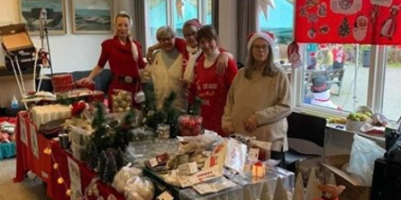 Fem personer der står ved et fyldt bord ved et julemarked