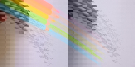 Streger lavet med blå, grøn, gul, orange og lyserød ved siden af hinanden og farveblyanterne