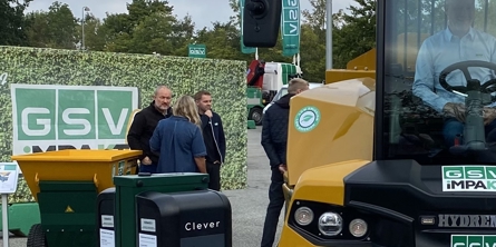 Tre mennesker der kigger på en gul gravko hvor en sidder på førersædet