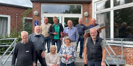 Ti ældre mennesker der står smilende foran Greve Borgerhus