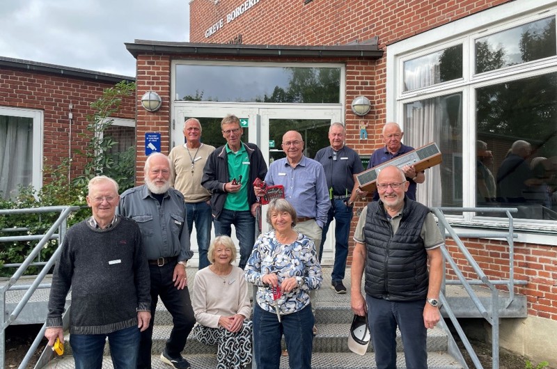 Ti ældre mennesker der står smilende foran Greve Borgerhus