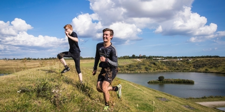 To drenge der løber op af en bakke i solskin