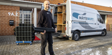 Mand fra Måtteskift der står med en måtte foran sin varevogn og et bur fyldt med måtter