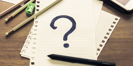 Blok med et spørgsmålstegn på og nogle blyanter