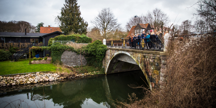 Elever der står og kigger udover en bred å fra en bro