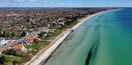 Luftfoto af Greve Strand. Til venstre ses by og strand. Til højre ses havet. 