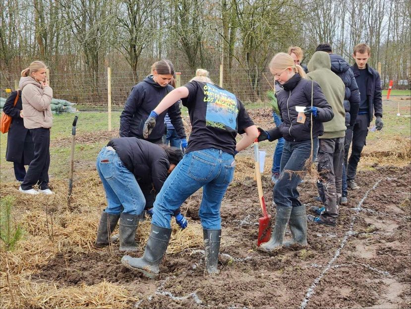 Elever der graver i jorden med gummistøvler på.