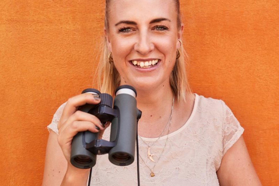 Vicky Knudsen der står og smiler med en kikkert i hånden