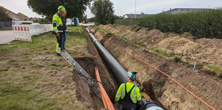 3 arbejdere der graver rør ned i jorden.