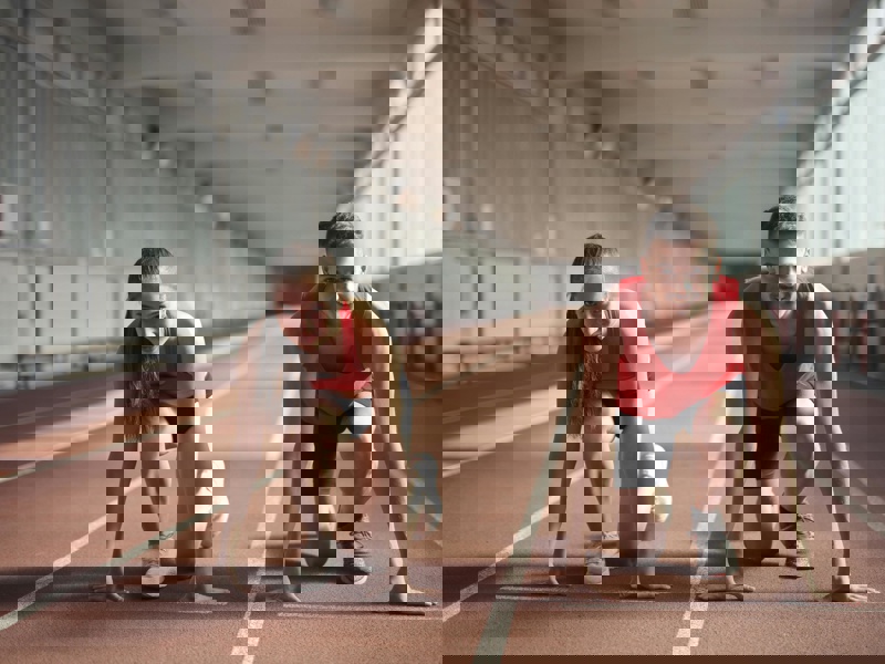 Ung mand og kvinde der sidder klar til at løbe på en løbebane