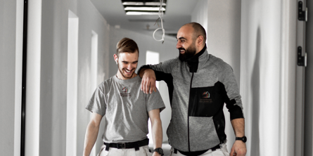 To håndværkere der går indenfor og griner