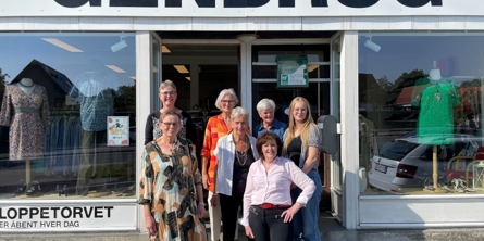 syv kvinder der står foran en genbrugsbutik