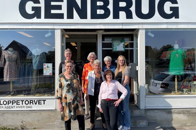 syv kvinder der står foran en genbrugsbutik